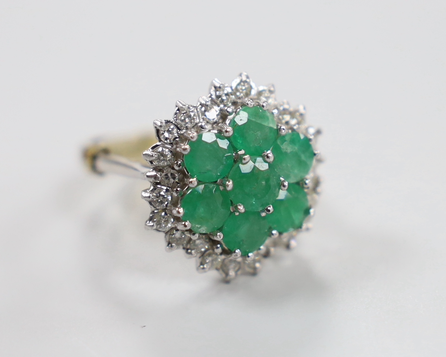 A modern 18ct white gold, emerald and diamond cluster set dress ring, size P/Q, gross weight 7.8 grams.